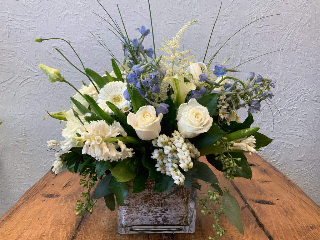 Peace & Light- Mix of White Florals with Blue Delphinium in a square glass vase