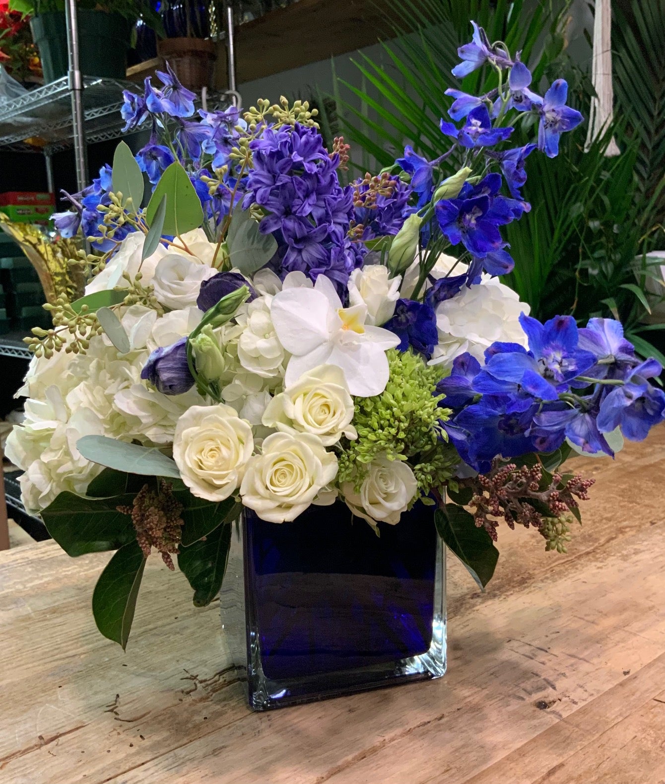 Blue & Prosper- Orchids, Blue Delphiniums & Spray Roses in a Blue Cube Vase